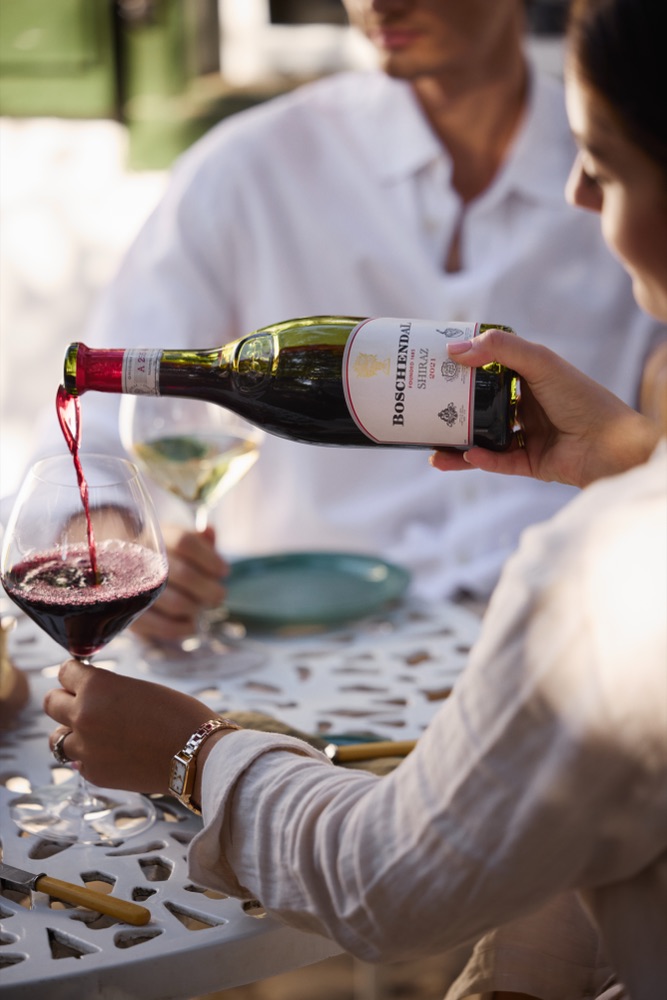 Pouring a glass of Boschendal 1685 Shiraz at an outdoor table on the estate
