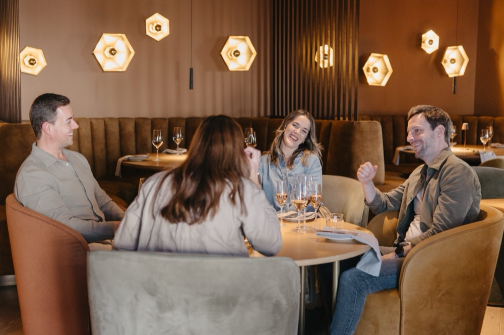 Guests laughing together over wine at the Magnolia Social Dining Lounge